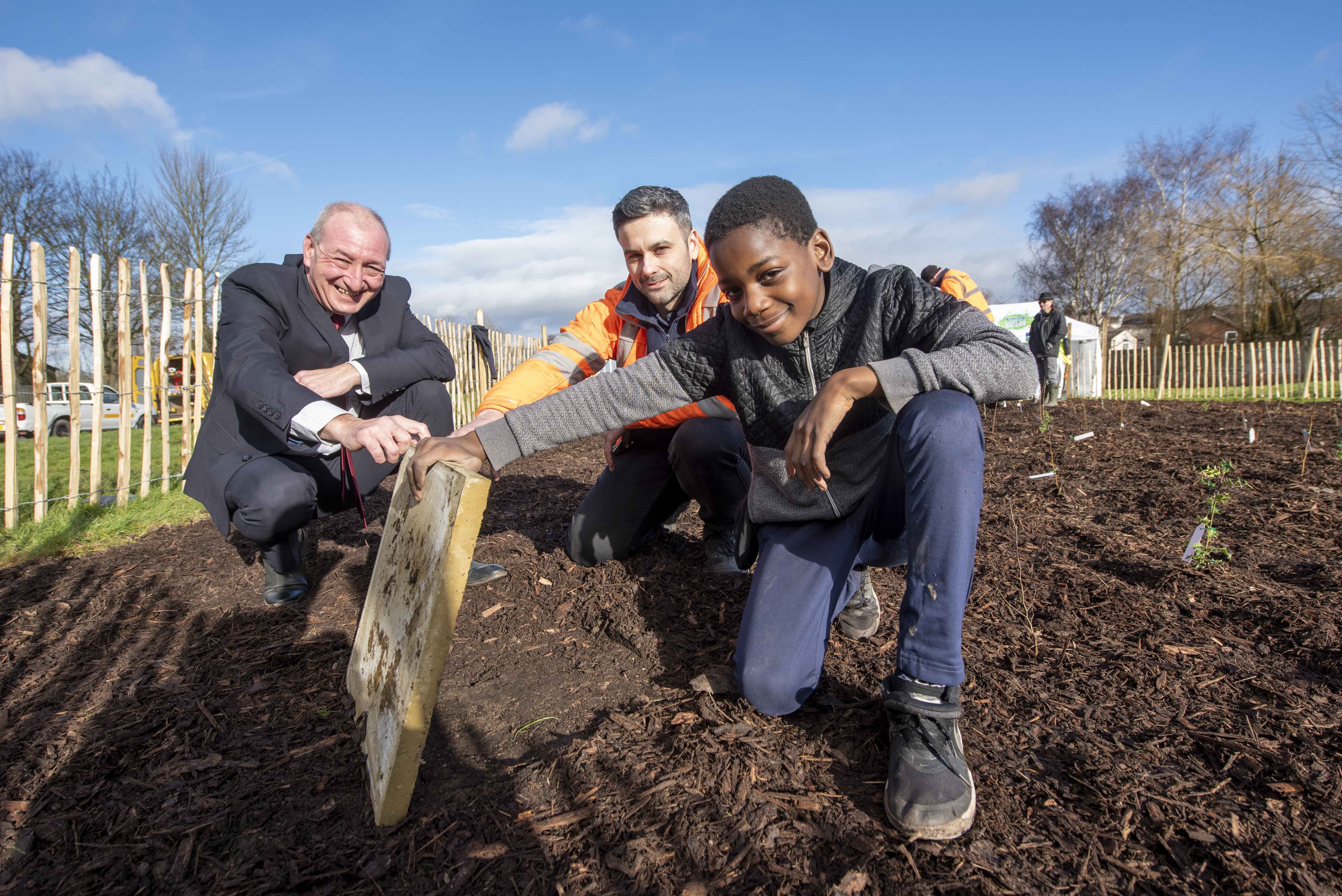 Investigating underneath the biodiversity tile at the Tiny Forest planting in Haggar Street. Blakenhall. are (from left) Councillor Steve Evans. cabinet member for city environment and climate change at City of Wolverhampton Council. Mitch Cross. Performance Manager at Severn Trent and Moses Bizimana from St Luke’s Primary School.